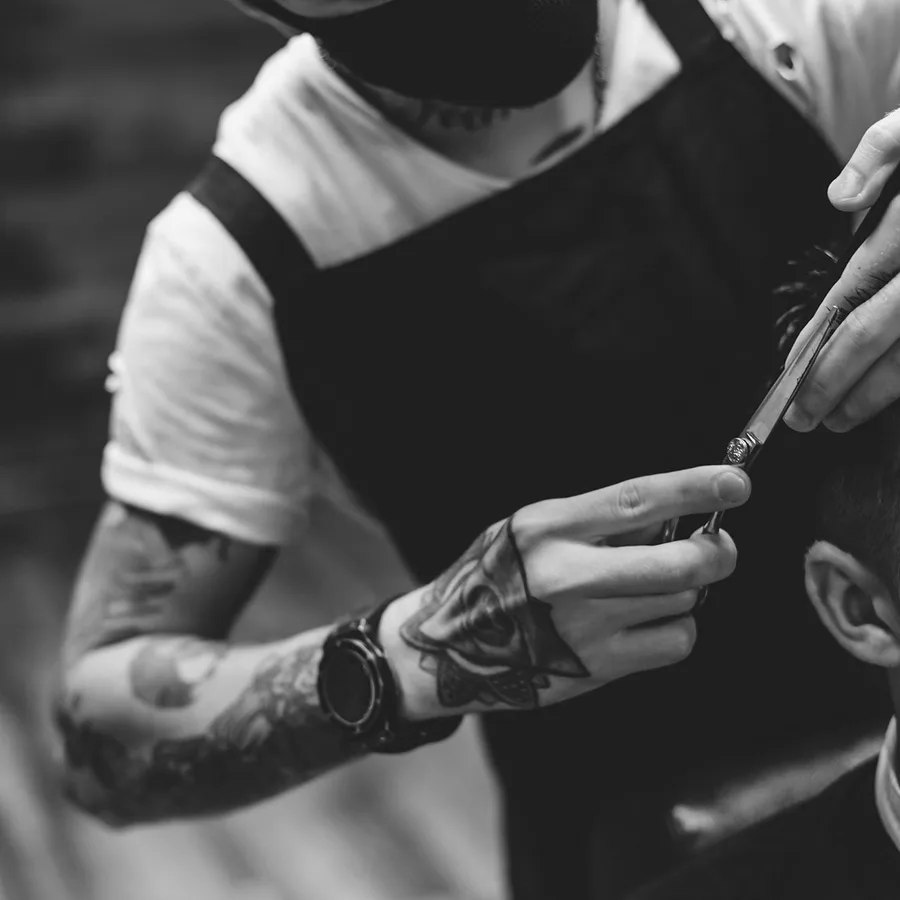 Barber performing a close razor cut in black and white