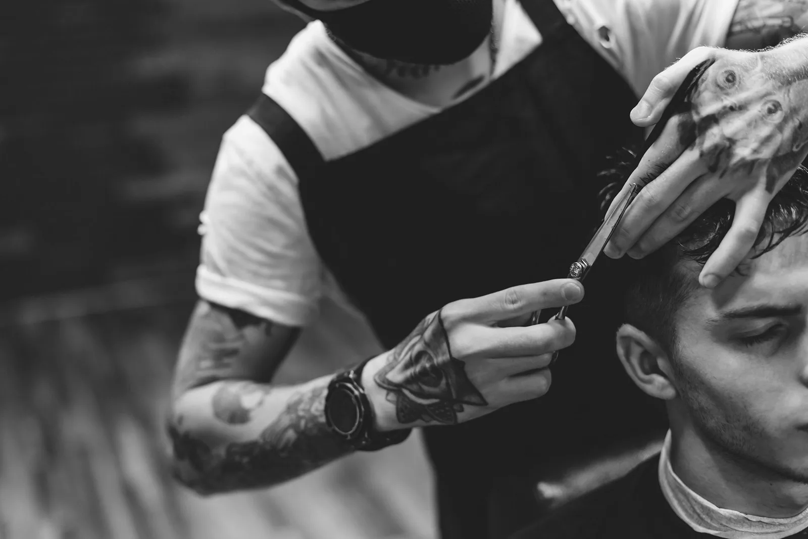 Barber giving a precise razor cut in black and white at Prestige Gentleman